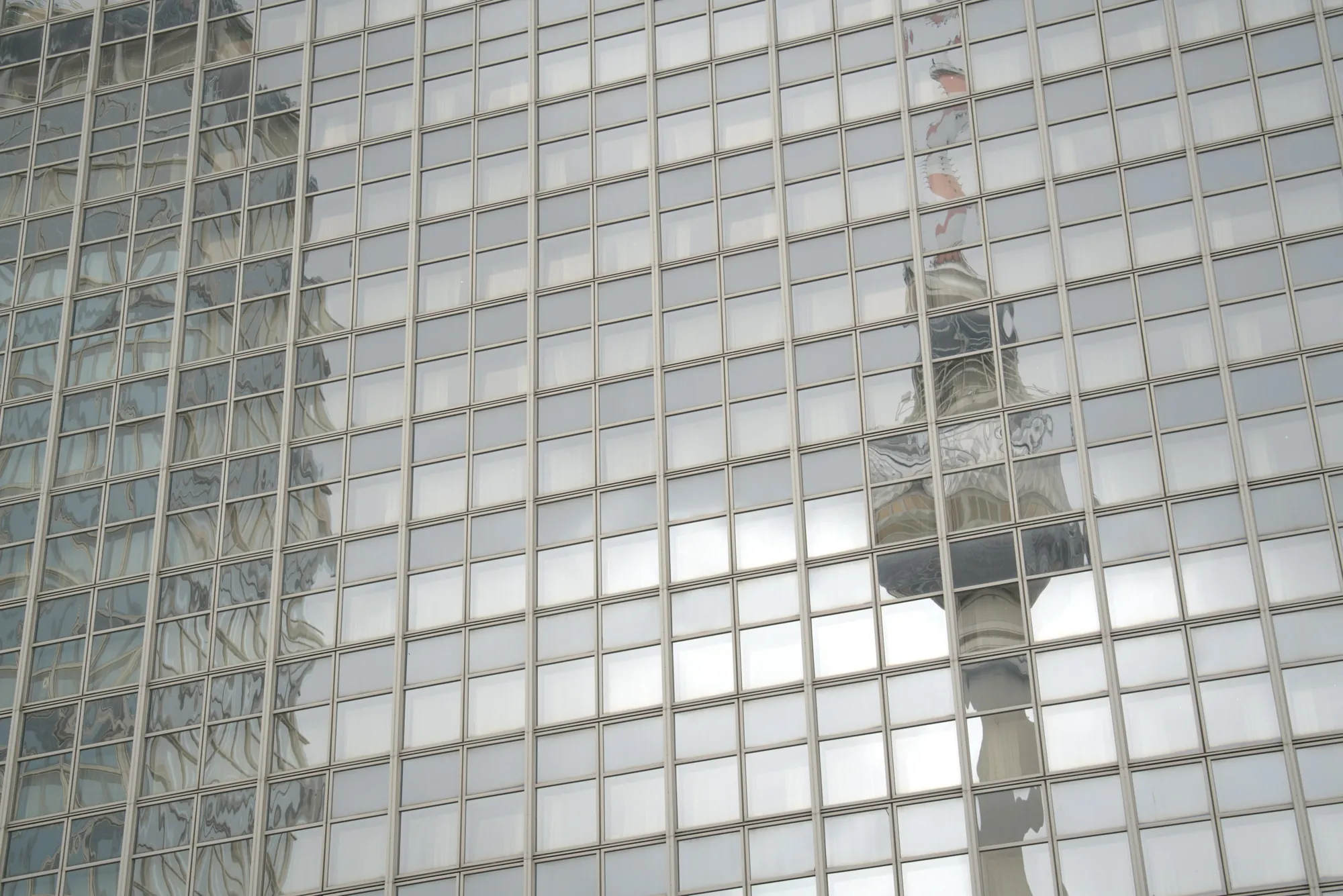Der Berliner Fernsehturm spiegelt sich im Raster einer Glasfassade.